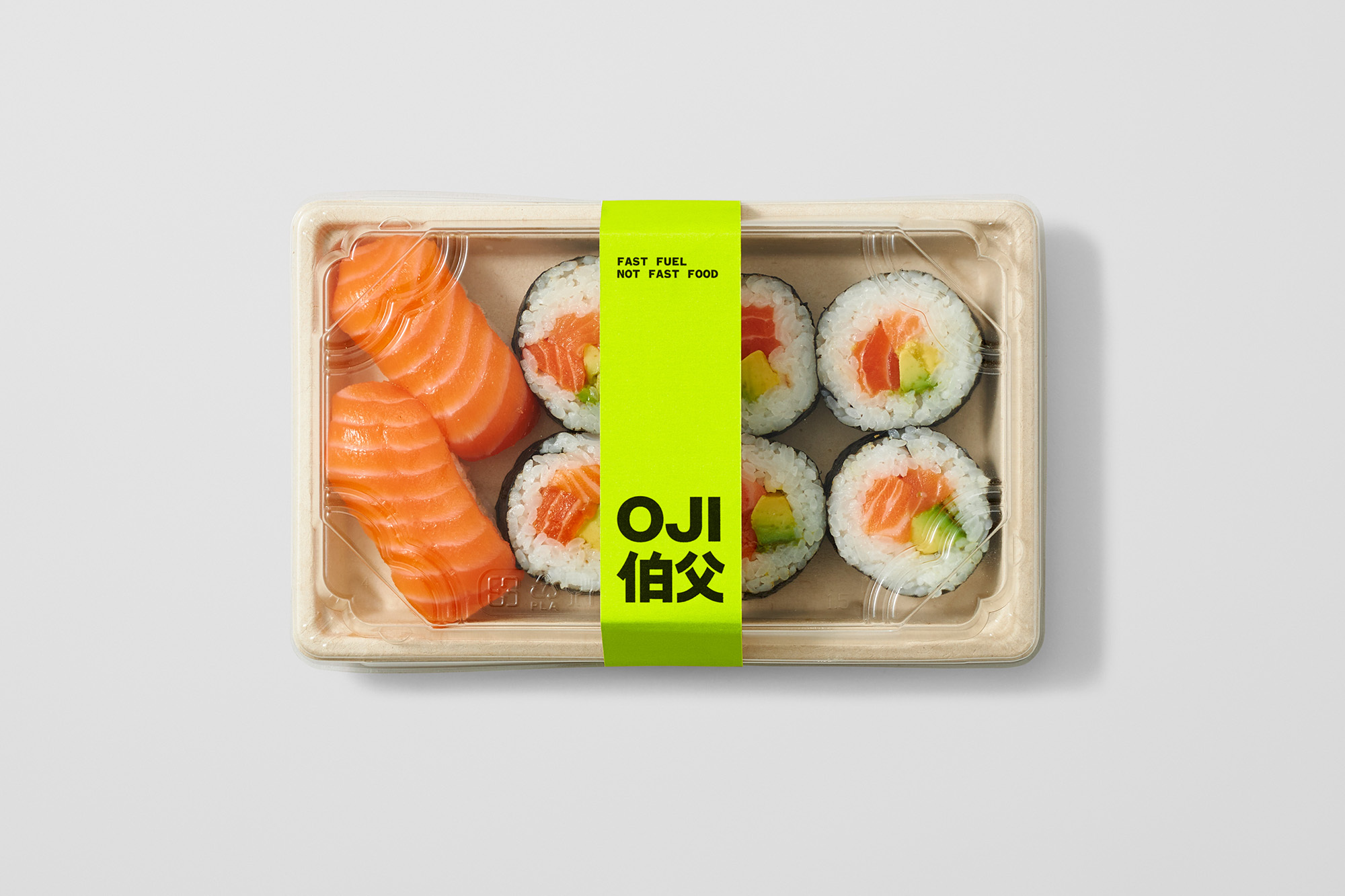 Overhead shot of a sushi takeout container featuring salmon nigiri and sushi rolls with bright green label on a plain white background.