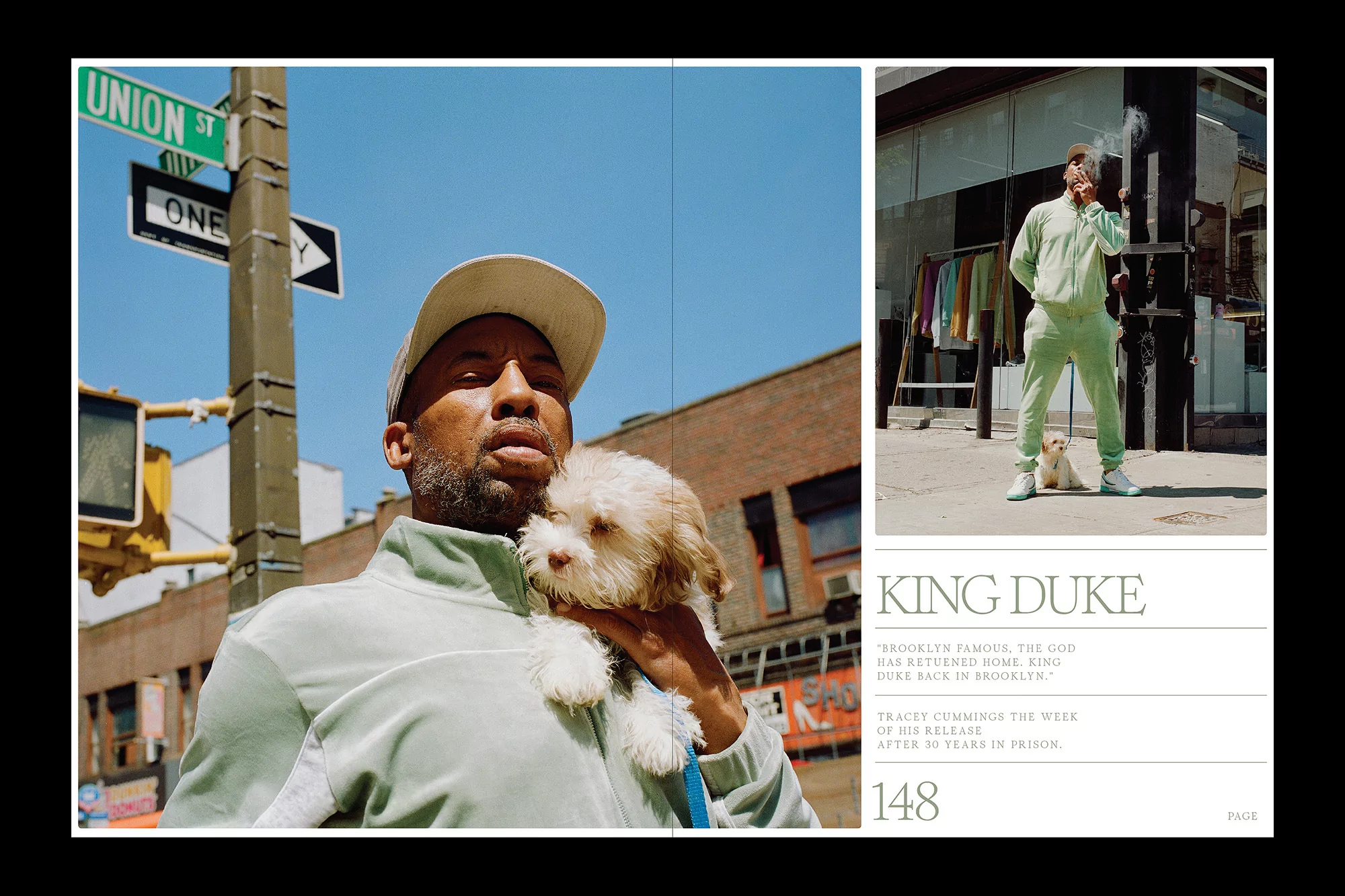 Man in a light green tracksuit holding a small dog on a city street with buildings and a street sign on a sunny day, portrait orientation.