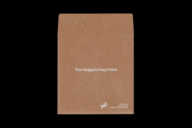 Tan-colored envelope with text about dog waste bags against a black background. Packaging with pet waste disposal information.