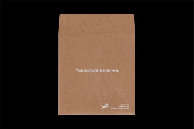 Brown paper mailing envelope with white typography centered on the front against a solid black background.