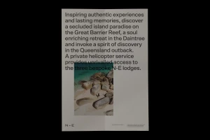A typographic brand identity poster featuring descriptive body text overlaying an aerial beach photograph showing smooth boulders on sand.