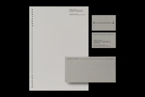 Minimalist corporate stationery set featuring letterhead, business cards, and envelope with grey and black branding.