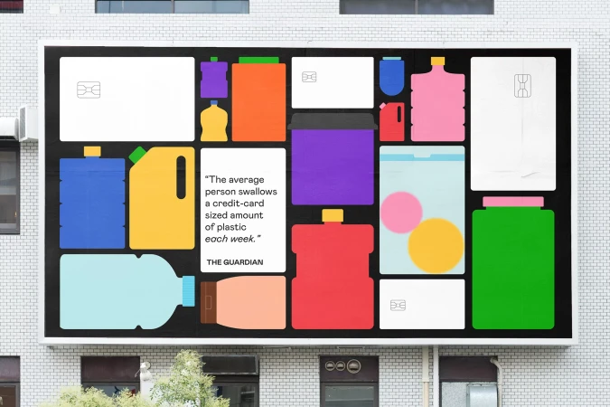 Eye-level shot of an advertising billboard with flat vector graphics of plastic containers and credit cards for a recycling campaign.