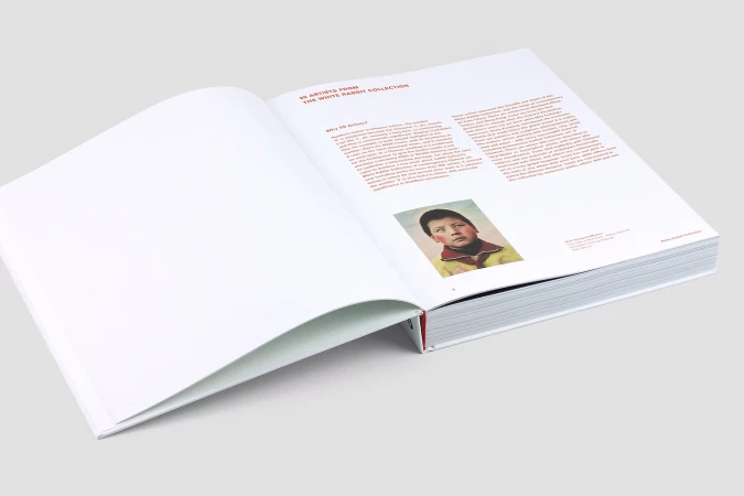 Open book displaying a page with the title '55 Artists from the White Rabbit Collection' and a portrait of a child.