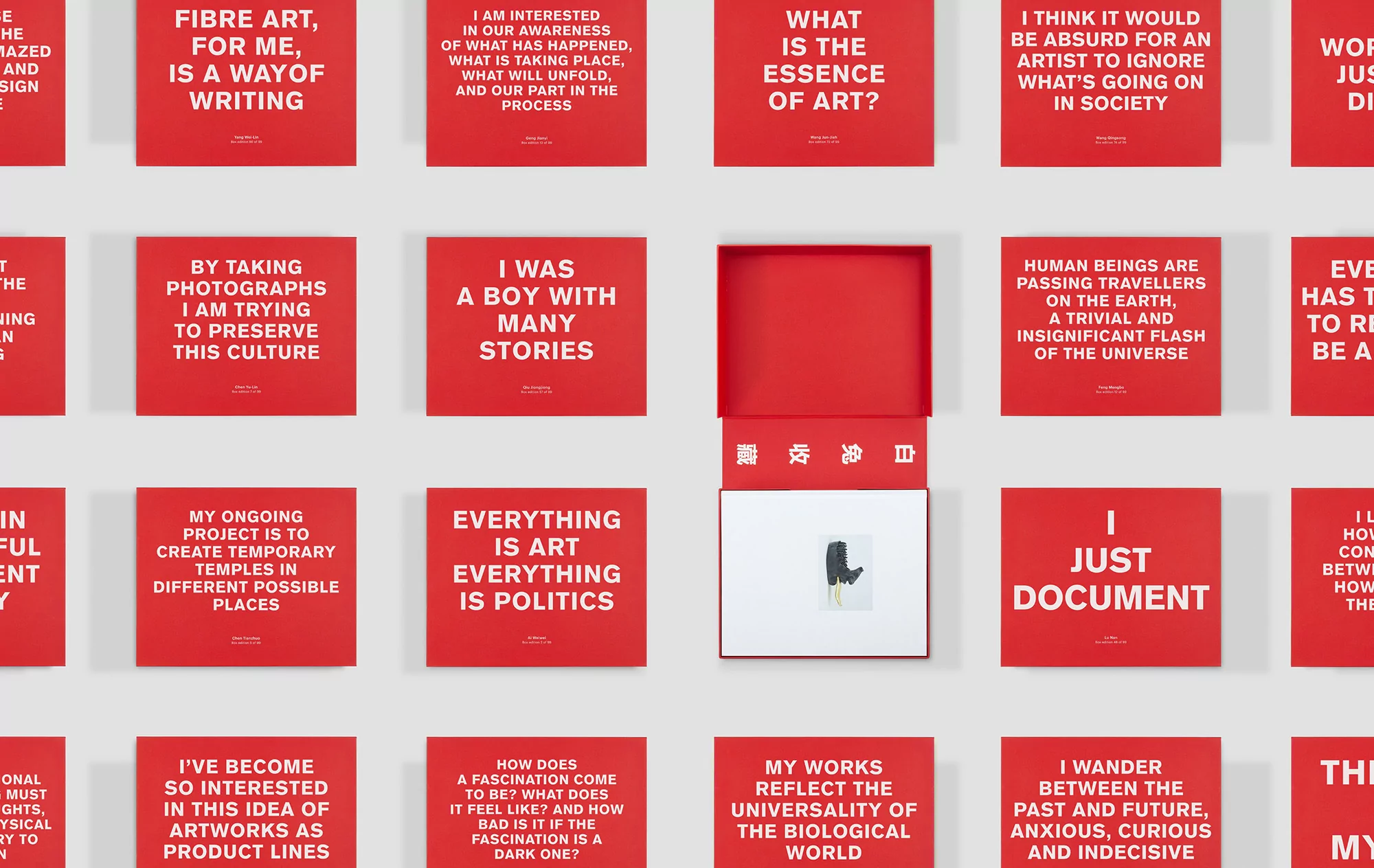 Close-up of red cards displaying textual quotes on a white surface. One red box is open with an illustration inside.