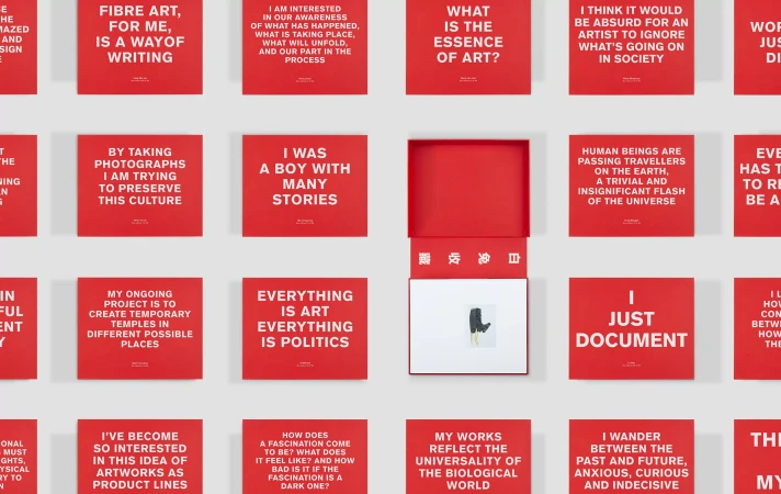 Close-up of red cards displaying textual quotes on a white surface. One red box is open with an illustration inside.