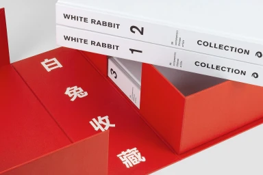 White Rabbit Gallery collection books resting inside a bright red presentation box with Chinese characters printed on the interior