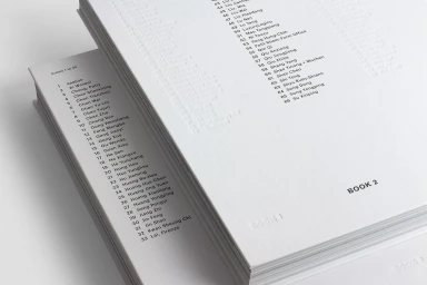 Stacked white art books with black typography and debossed text on clean white background