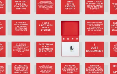 Flat lay grid of red rectangular cards featuring white text quotes with an open red box containing an artwork.