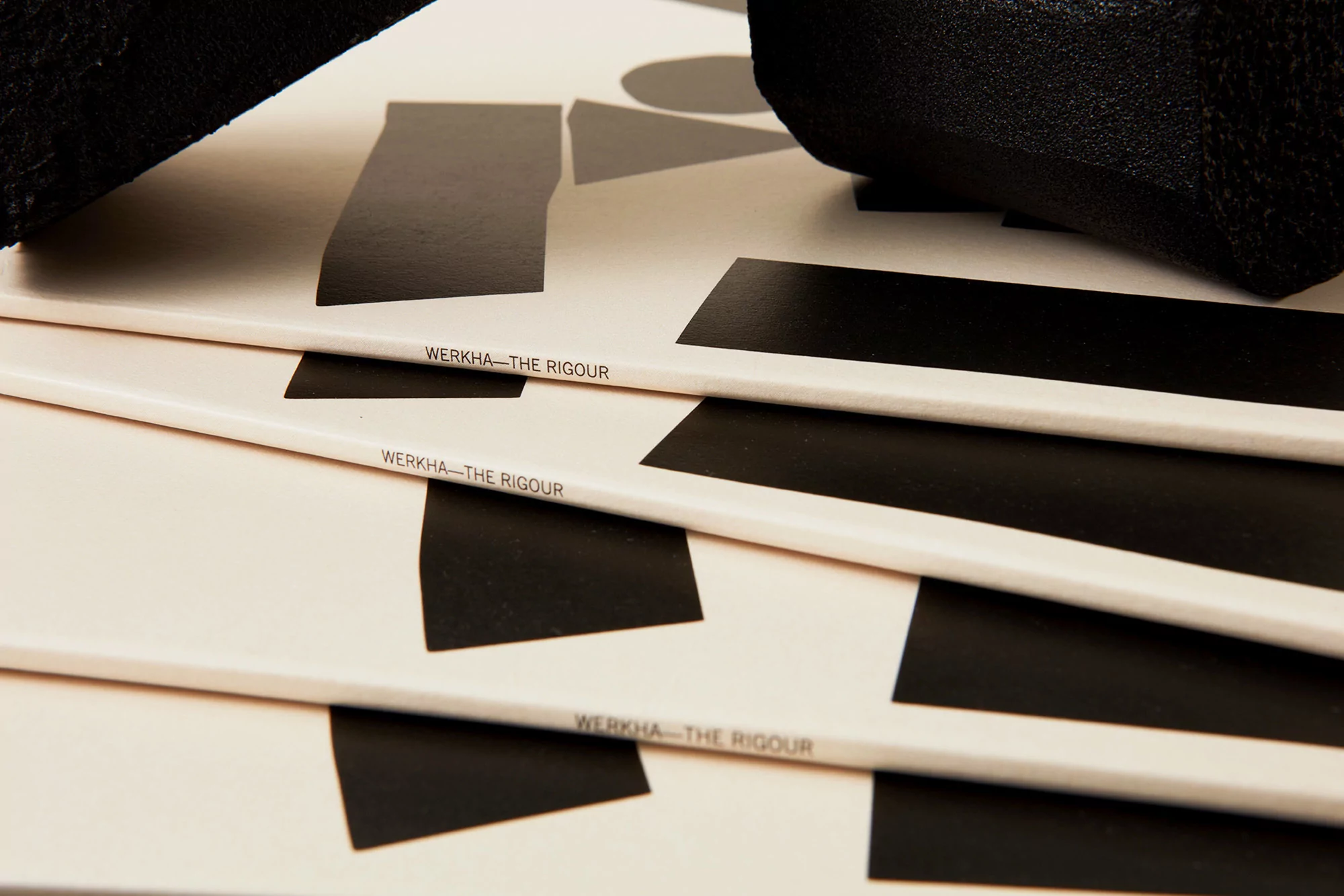 Stack of Werkha - The Rigour album covers with geometric black and white design, creating a modern and artistic visual.