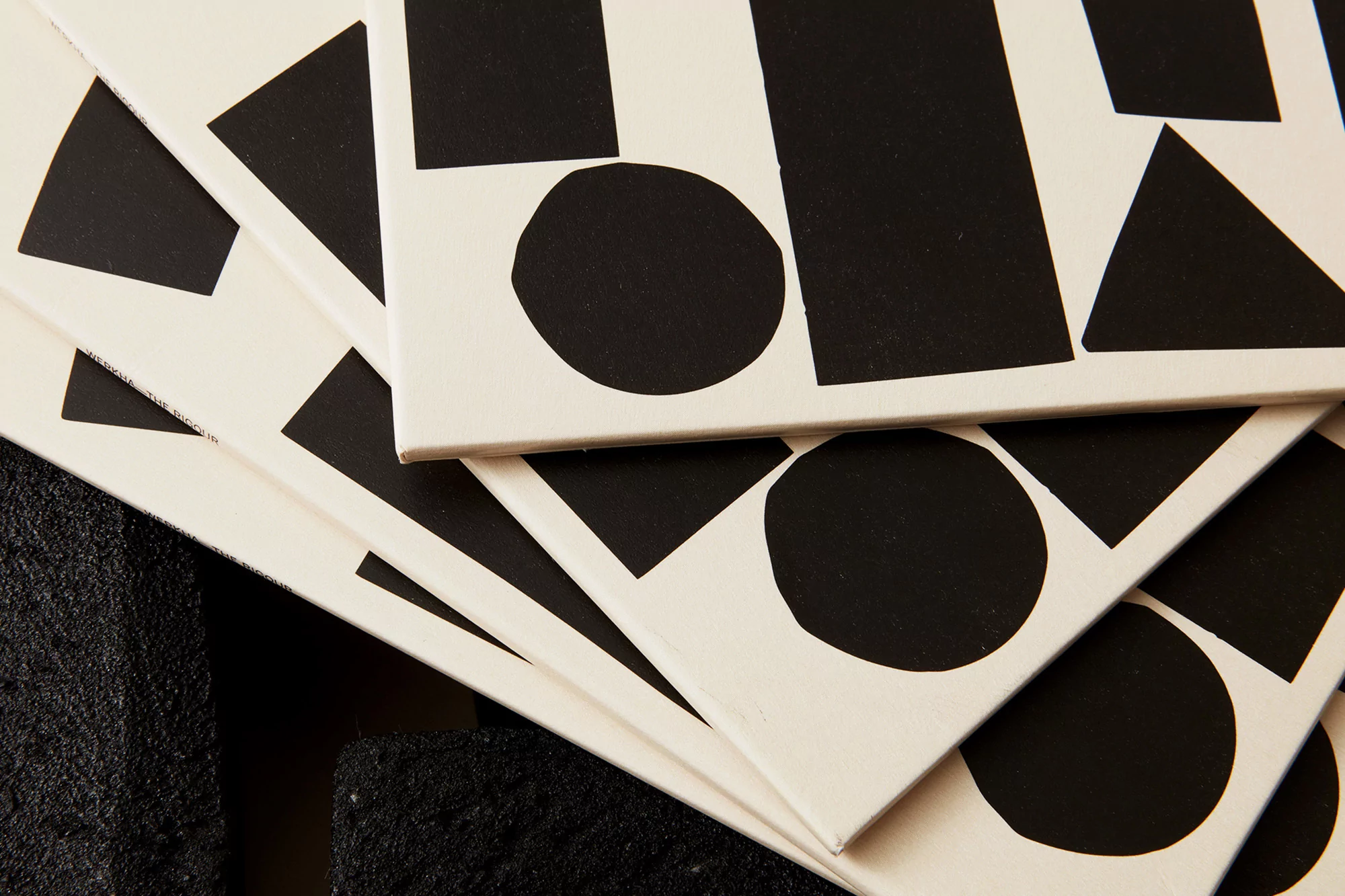 Monochromatic geometric art featuring black squares, triangles, and circles arranged on layered white square canvases.