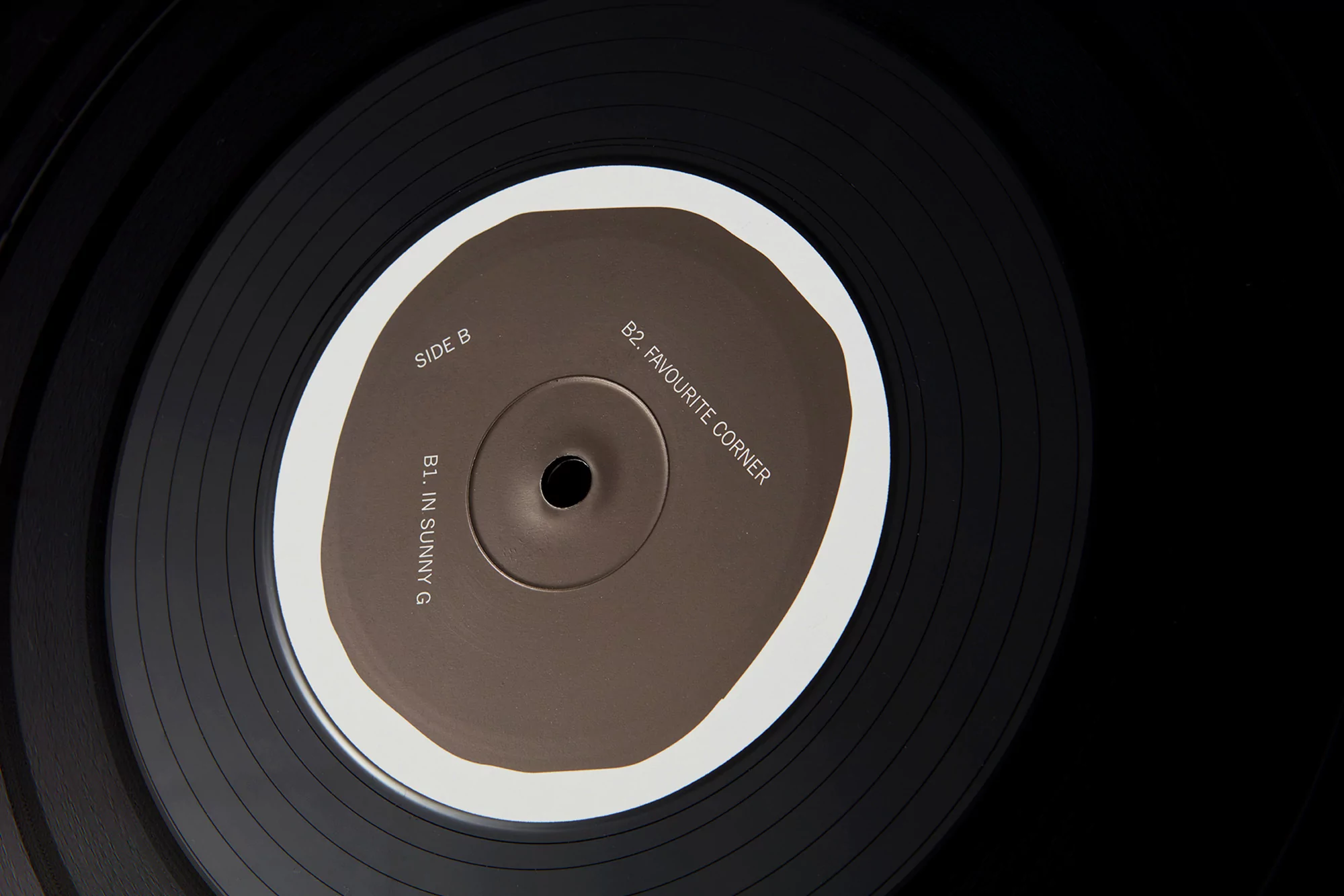 Vinyl records stacked displaying album label with track titles in minimal, dark aesthetic, suitable for music industry content.