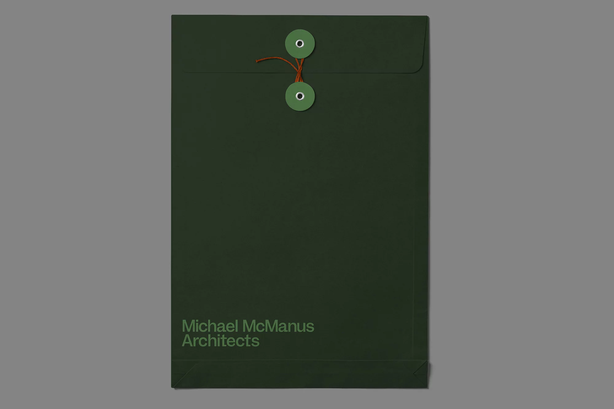 Dark green string and button envelope featuring the text, 'Michael McManus Architects' on a neutral gray background.