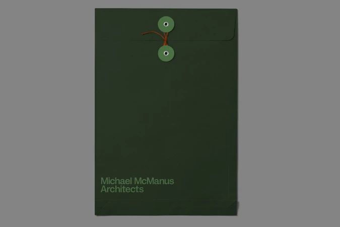 Dark green string and button envelope featuring the text, 'Michael McManus Architects' on a neutral gray background.
