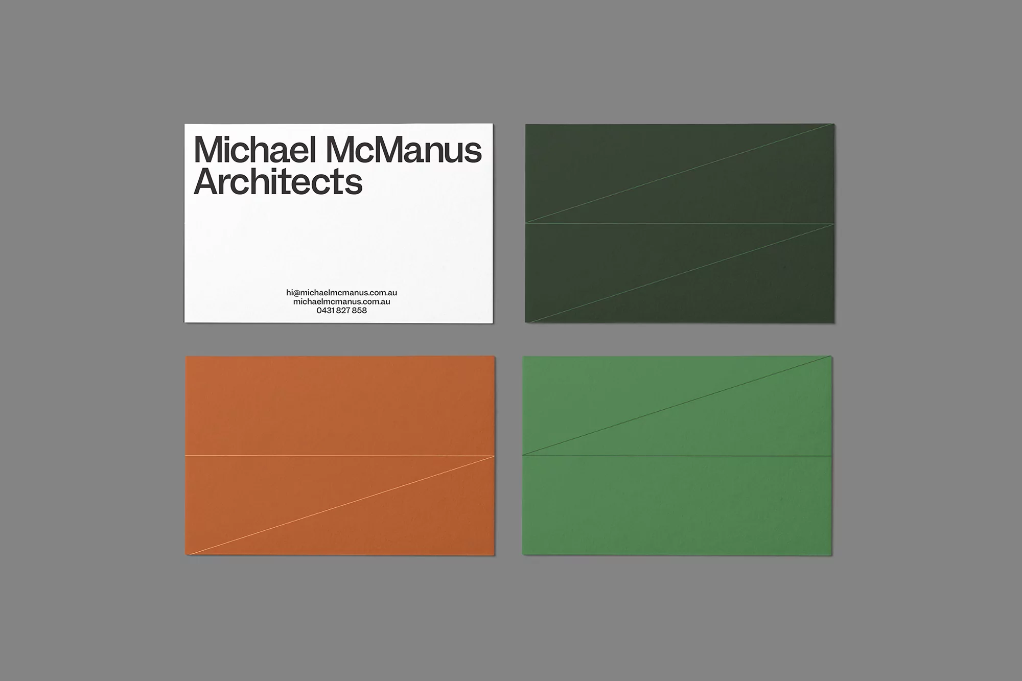 Four business cards with geometric design in white, green, and orange on a gray background, showcasing architectural design firm identity.