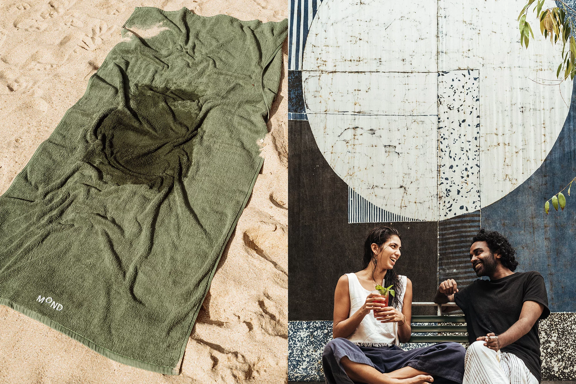 A green towel sits on tan sand beside a couple seated on a bench with an art wall in the background enjoying an outdoor moment.