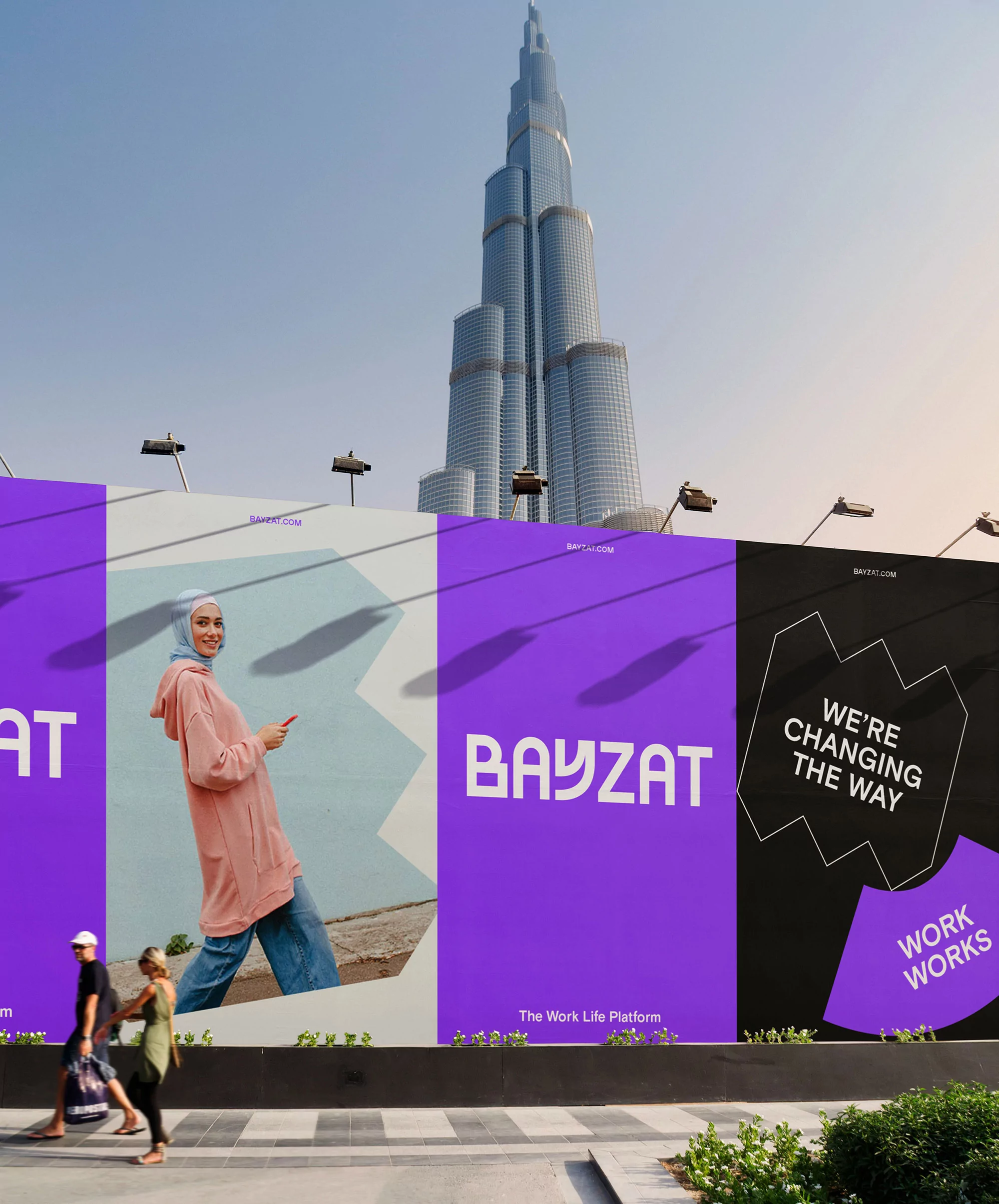 Billboard featuring an image of a woman, set against the backdrop of the Burj Khalifa skyscraper and a clear blue sky in Dubai.