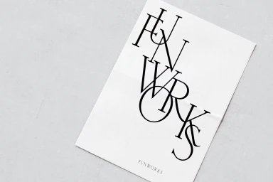 A white paper sheet with large black serif typography spelling Funworks against a light grey surface