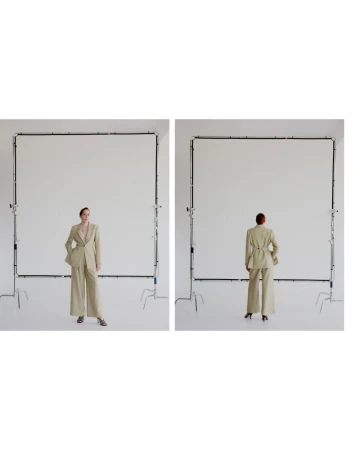 Front and back views of a female fashion model wearing a light tan suit in a studio setting, standing in front of white screens.
