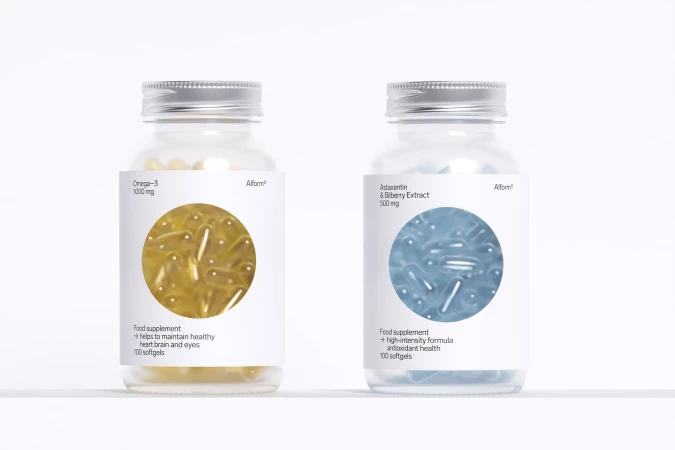 Two transparent glass supplement bottles, one with yellow capsules and one with light blue capsules, isolated on a white background.