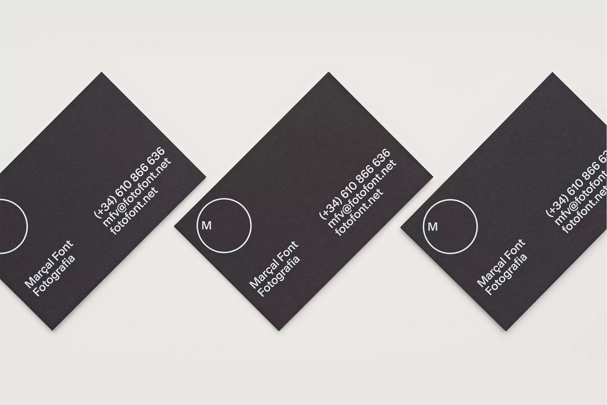 Close-up of three black business cards with white text and logo, arranged diagonally on a white background, promoting Marçal Font Fotografia.