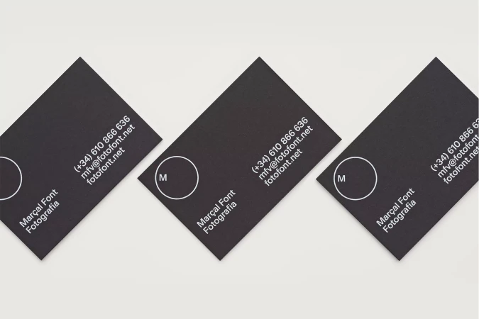 Close-up of three black business cards with white text and logo, arranged diagonally on a white background, promoting Marçal Font Fotografia.