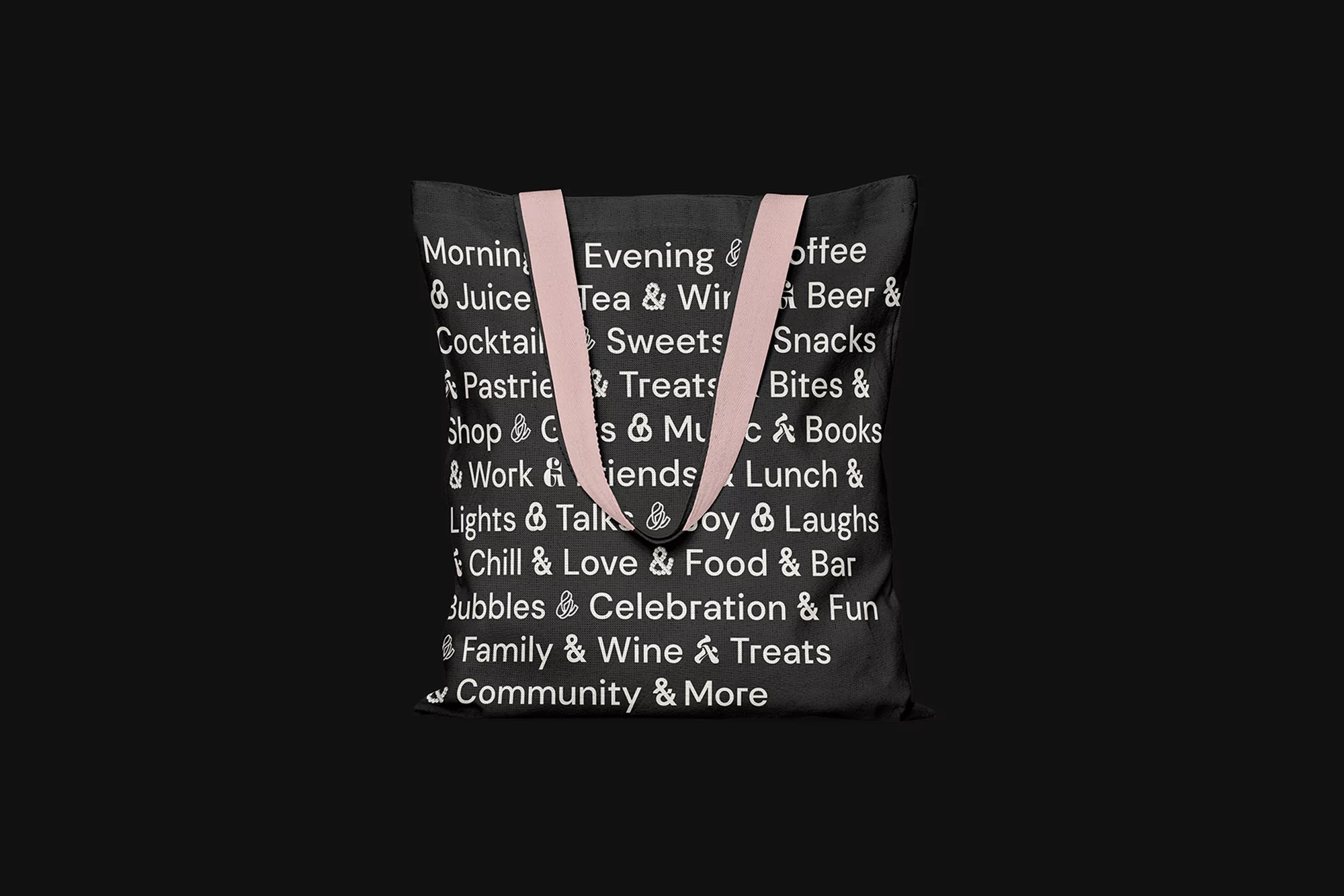 Black tote bag with pink handles and text graphics on a black background. Stylish, reusable bag for shopping and everyday use.