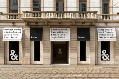 Classical stone building exterior featuring branded awnings and large street-level windows with ampersand graphics for Sheraton
