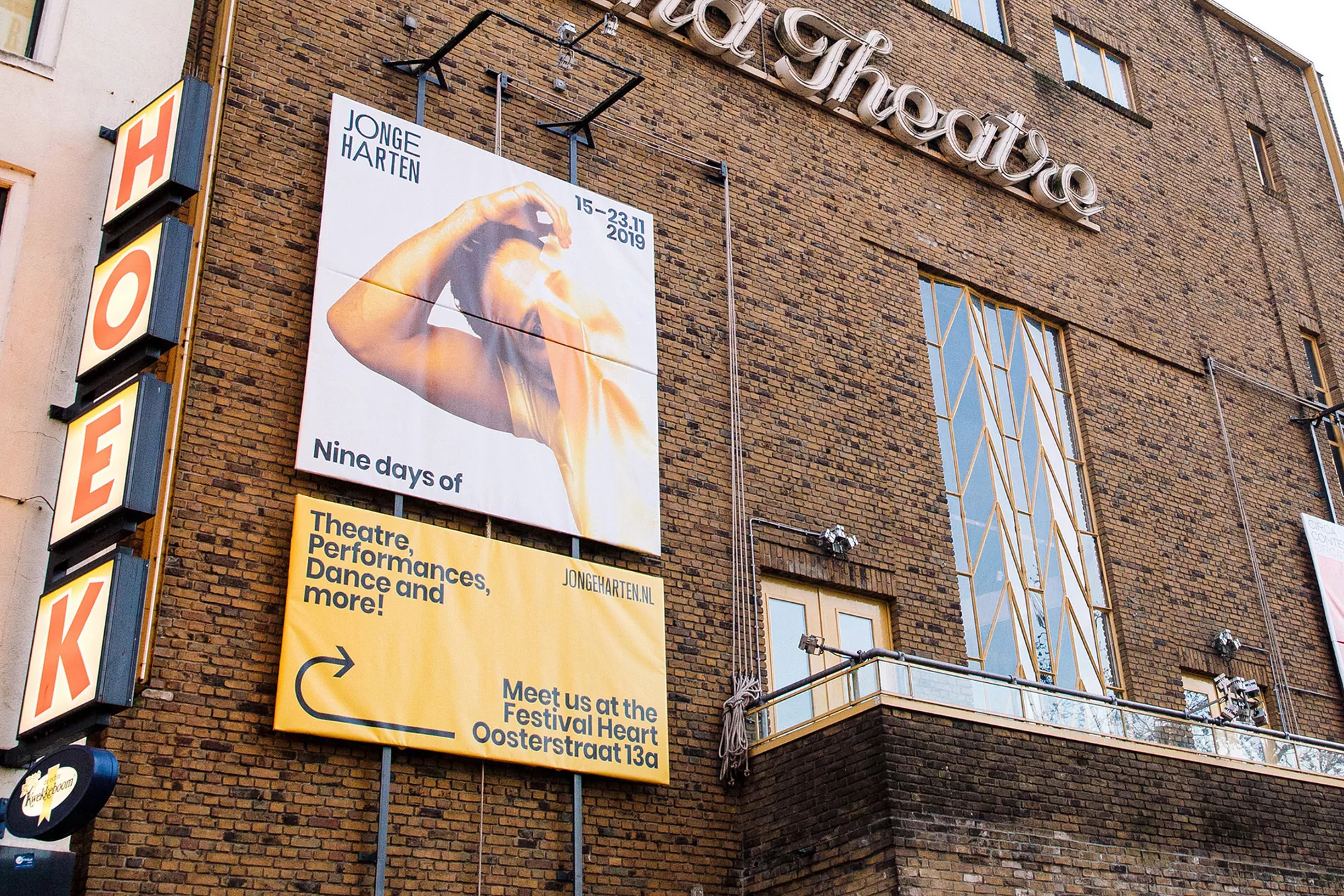Exterior shot of brick theatre featuring vibrant posters advertising 'Jonge Harten' festival, enhancing the building's facade.