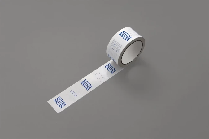 Roll of white custom-branded adhesive tape with repeated 'Batera' logo on a solid gray background for packaging and branding projects.