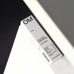 OM skincare product box angled on a geometric surface with black and white tones