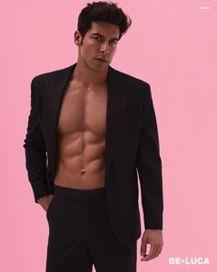 Model Andrea Denver wearing an open black suit jacket against a solid pink background for DELUCA Magazine.