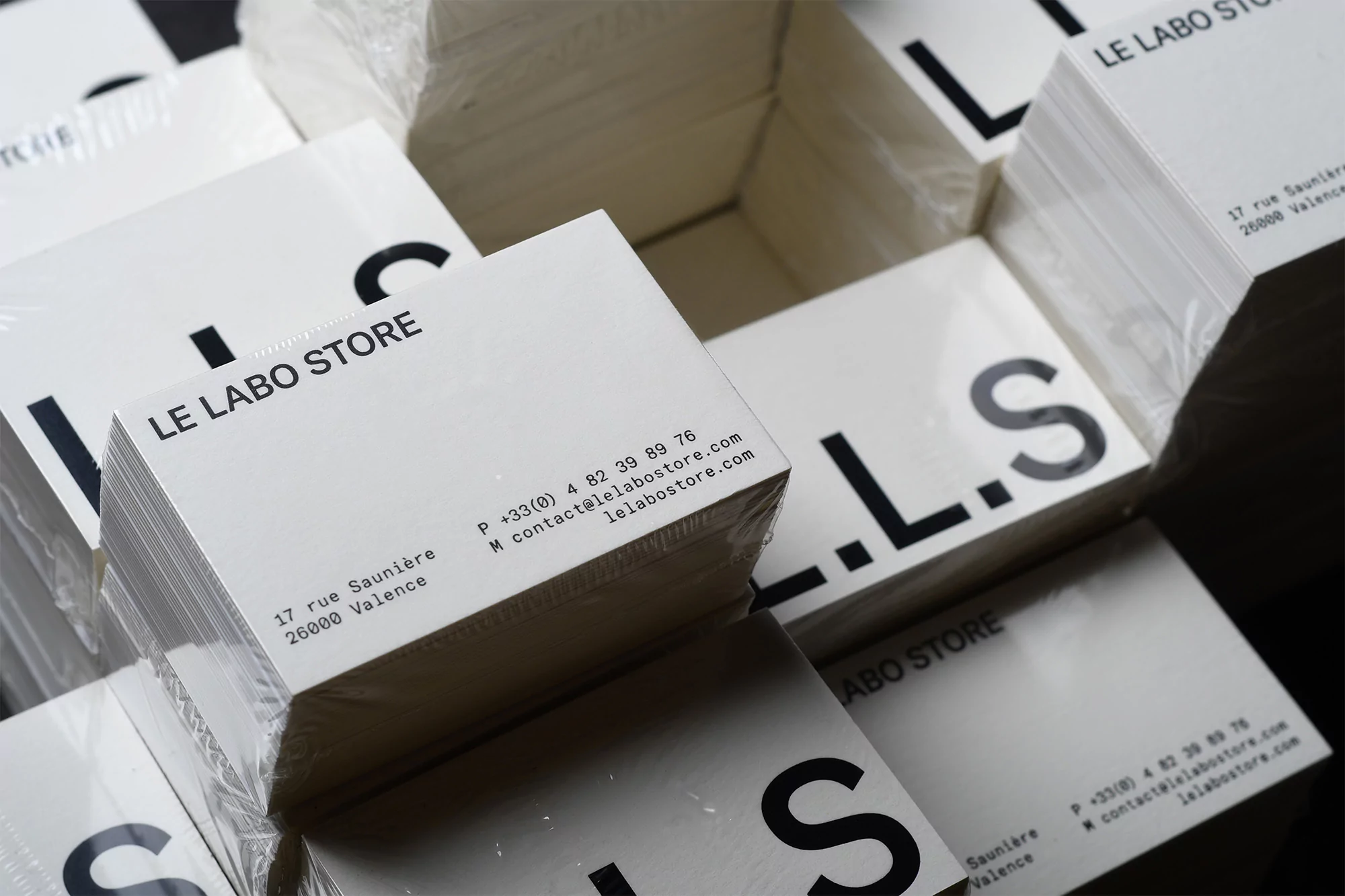 Stacks of Le Labo Store business cards show the brand logo, contact information, and address printed on white cardstock in a close-up studio shot.