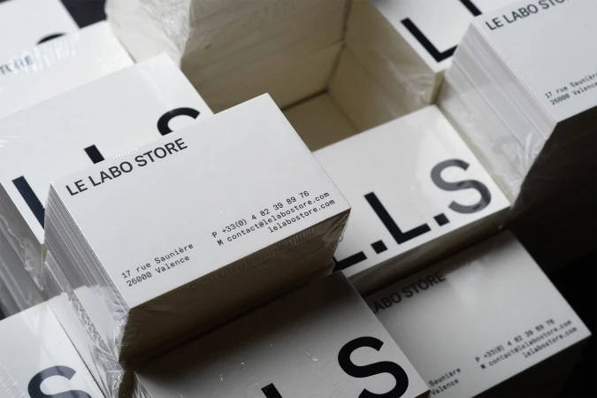 Stacks of Le Labo Store business cards show the brand logo, contact information, and address printed on white cardstock in a close-up studio shot.