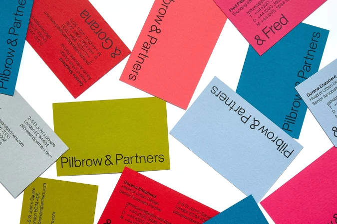 Colorful business cards for Pilbrow & Partners scattered across a white background