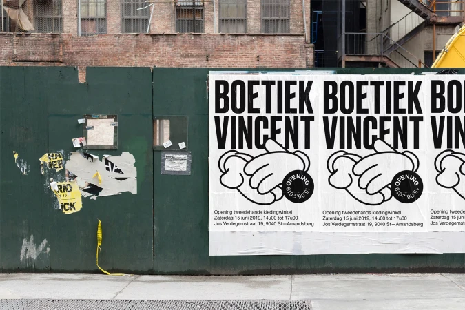 Outdoor posters on a green wall feature bold text and cartoon hands promoting 'Boetiek Vincent', advertising a secondhand clothing store opening.