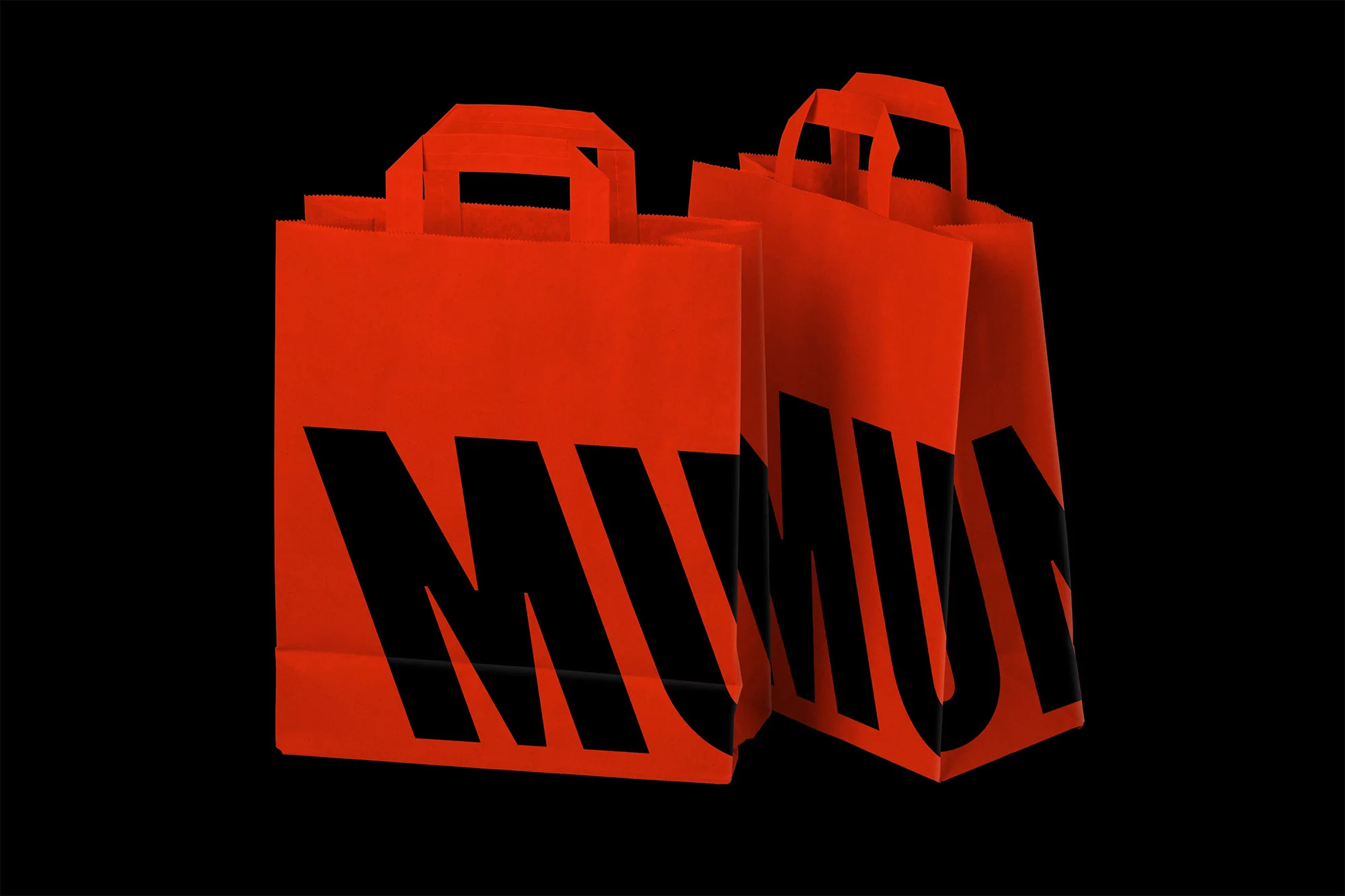 Two vibrant orange paper shopping bags with bold black diagonal lettering stand against a stark black backdrop, emphasizing modern retail design.