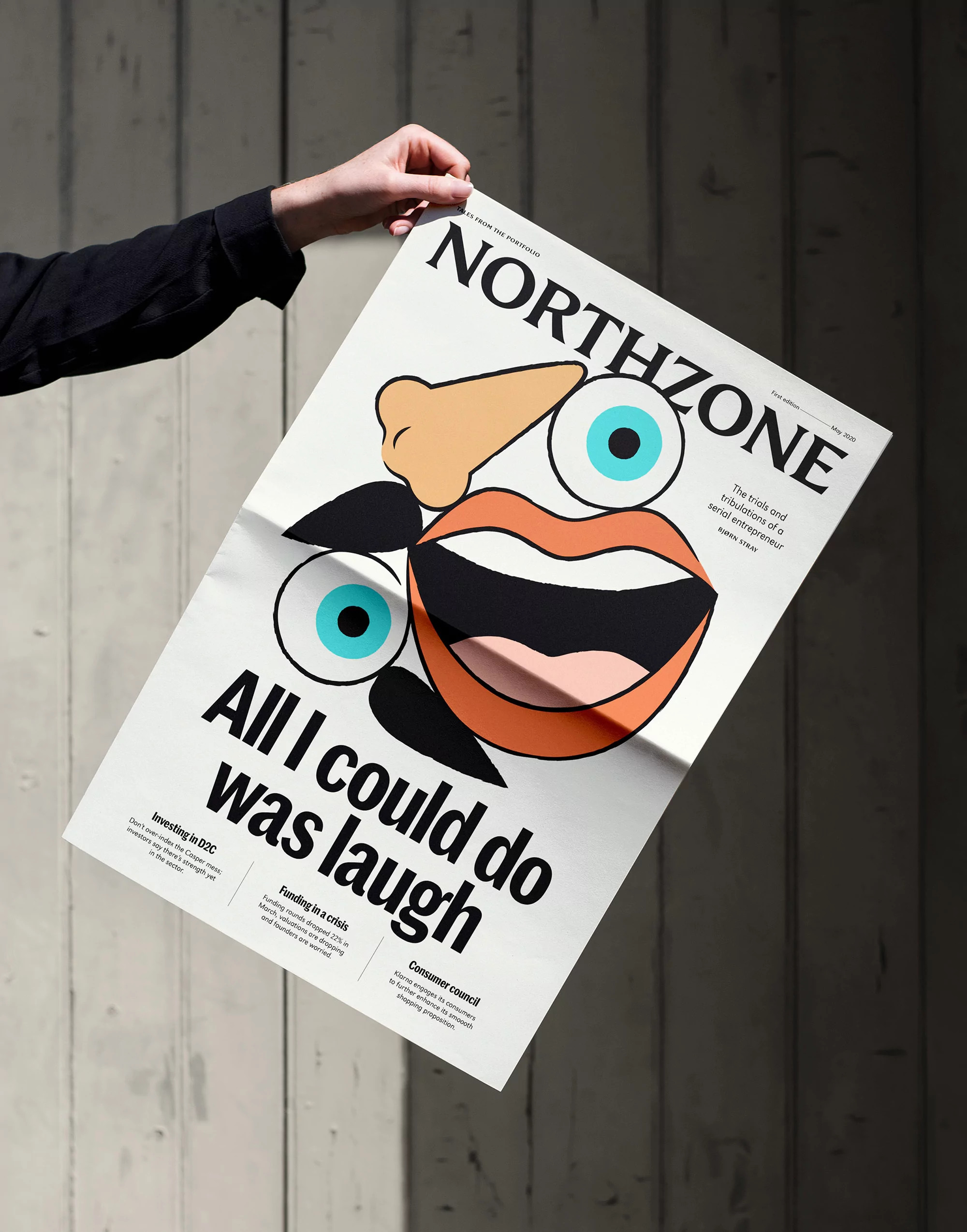 Hands holding a printed poster featuring Northzone branding and bold abstract illustrations against a wooden wall background.