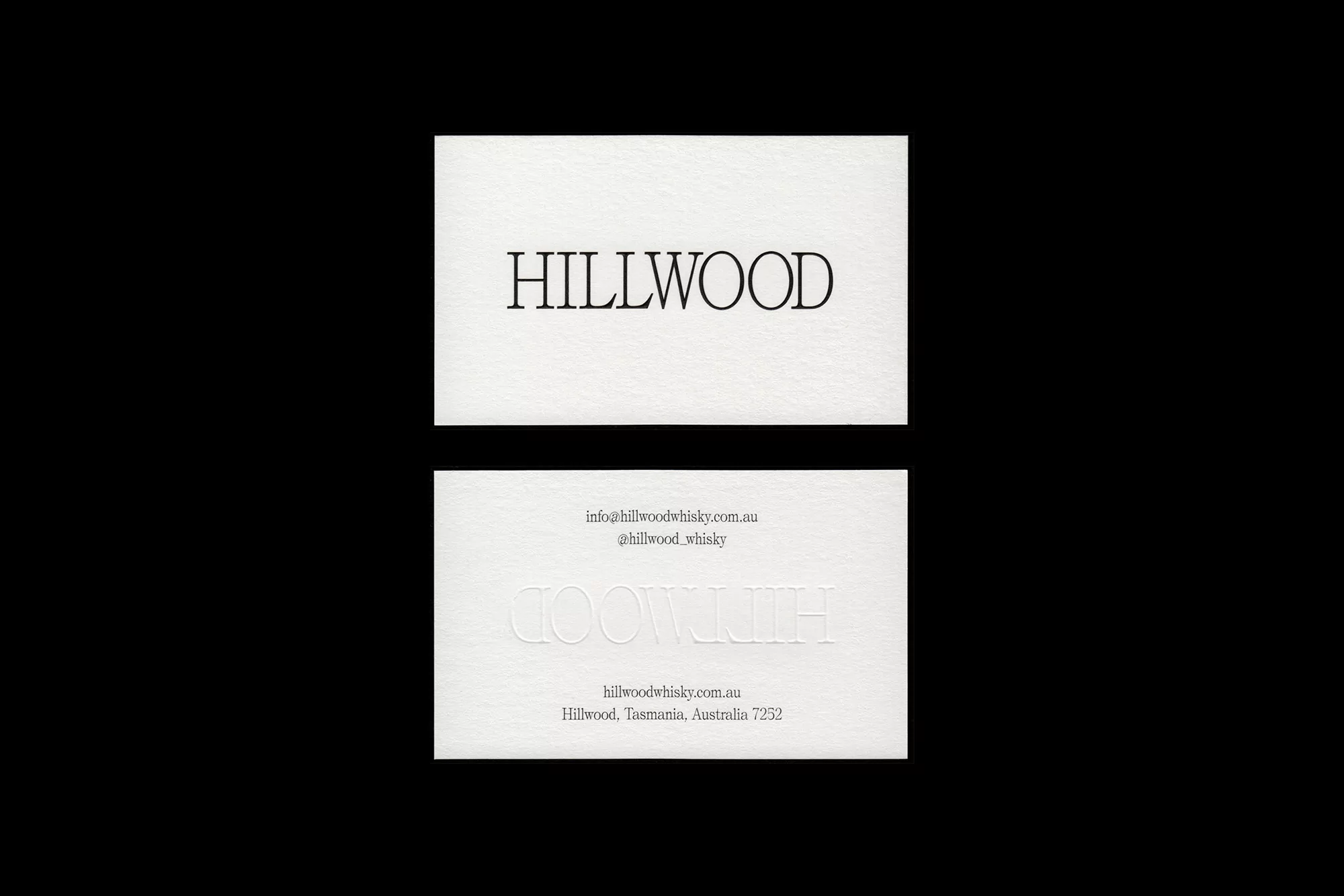 Two white business cards with black and embossed text on a black background, elegant and minimal design for Hillwood Whisky.