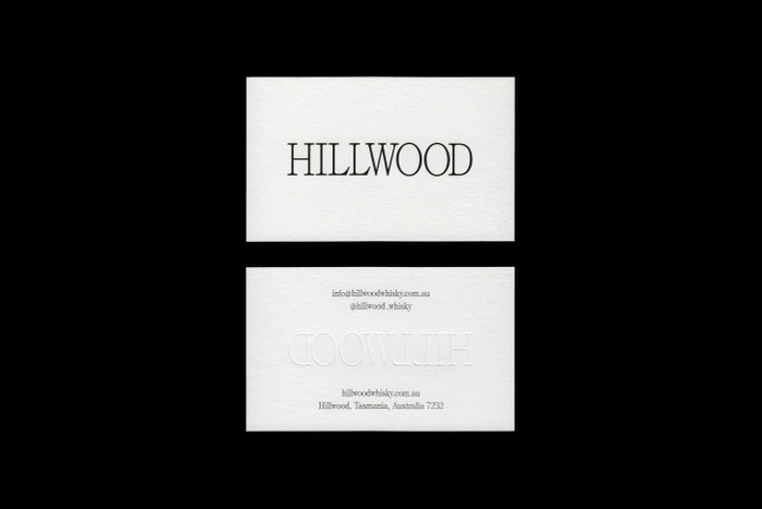 Two white business cards featuring Hillwood branding and typography centered against a dark black background.