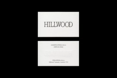 Two white business cards featuring Hillwood branding and typography centered against a dark black background.