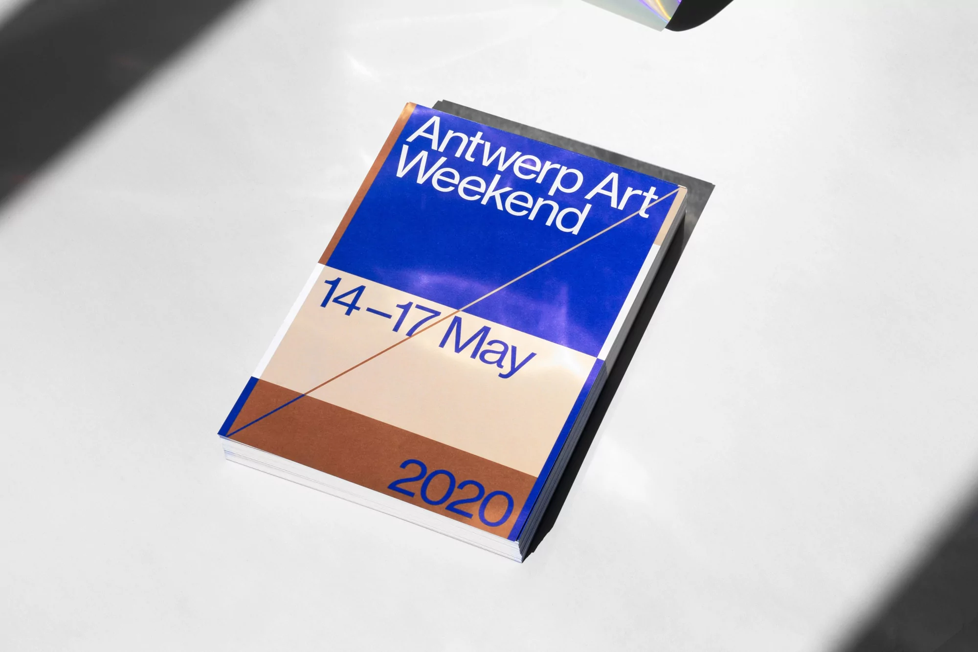 Art book for Antwerp Art Weekend 2020 with blue, beige and brown design on a white surface with light and shadow.