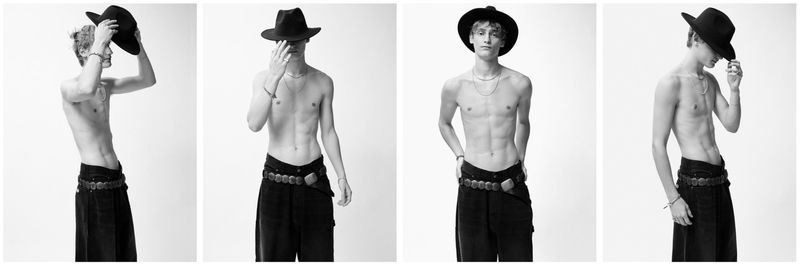 Black and white fashion-style shot of a shirtless, slim male model wearing a cowboy hat and stylish black jeans with a belt.
