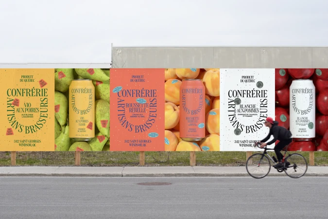 Eye-level shot of Confrérie canned drinks advertising panels outdoors, with a cyclist in motion, highlighting branding, typography, and product appeal.