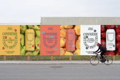Billboard posters featuring Confrerie Artisans Brasseurs beverage cans with a cyclist passing on the street