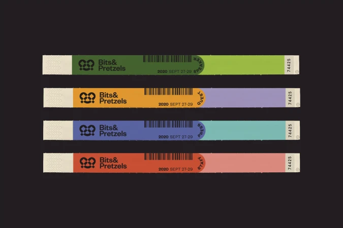 Promotional image of four different colored wristbands from the Bits & Pretzels conference. The wristbands are displayed against a dark background.