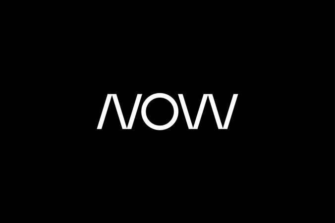 Bold white 'NOW' typography against a stark black background, minimalist design emphasizing modernity and simplicity in a studio setting.