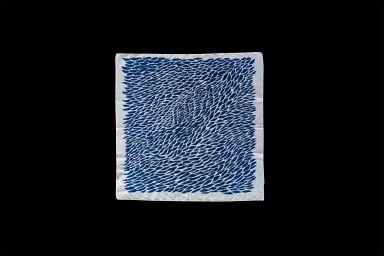 Square white textile piece featuring an intricate repeating pattern of small blue brushstroke shapes centered on a dark ground.