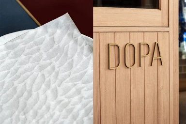 Close-up split image showing a textured white paper sheet and wooden panel with the brass letters DOPA.