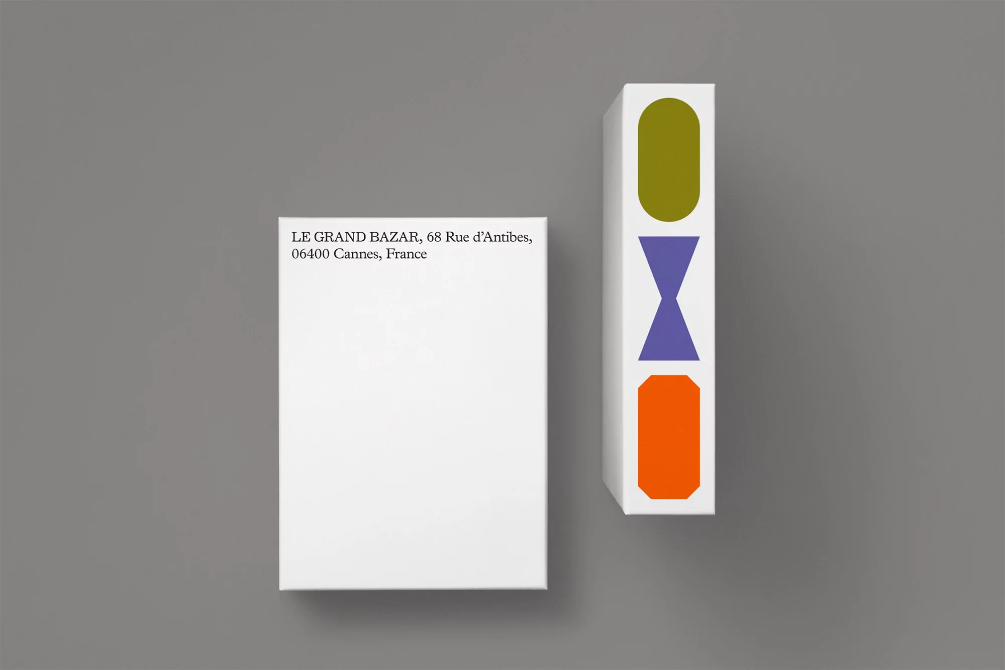 Modern product photography features two white rectangular boxes against a grey background, one adorned with colorful geometric shapes.